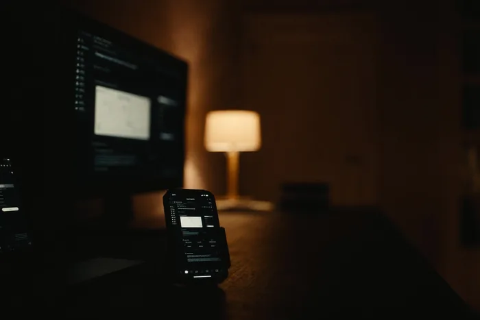A phone and a laptop side by side, an inbound message thread open.