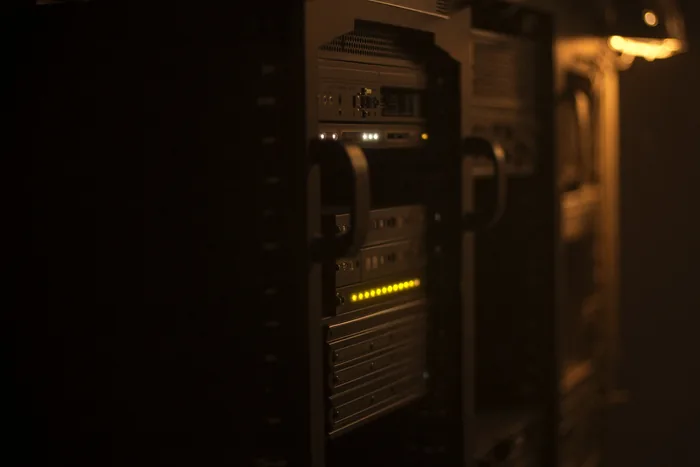 Server racks lit warm from within, cabling dressed down the rail.
